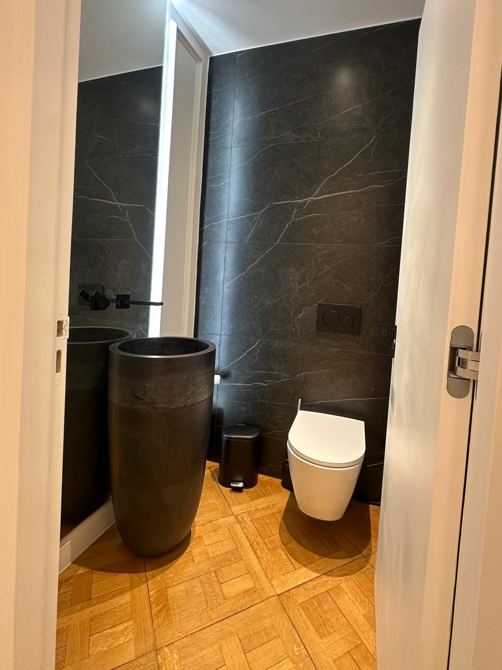 WC invité du duplex Périer : vasque totem sombre, WC suspendu et mur en pierre noire
