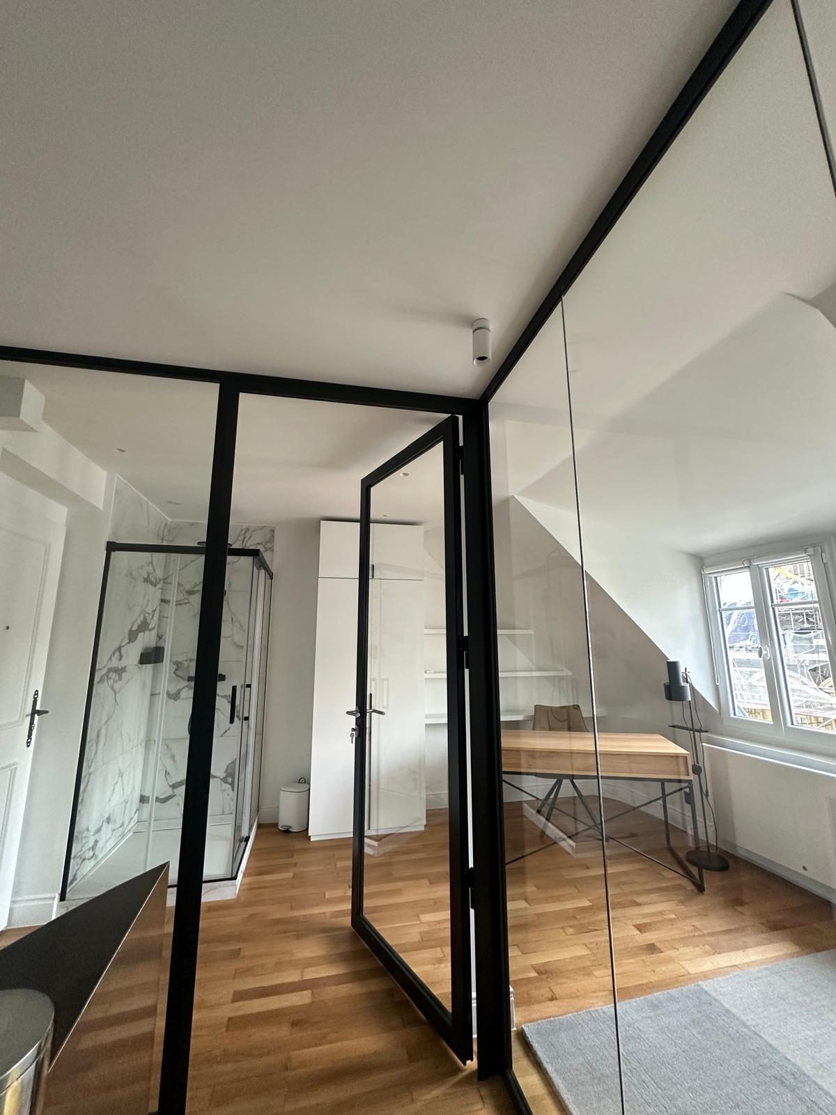 Espace sous pente du duplex Périer : paroi vitrée noire et bureau